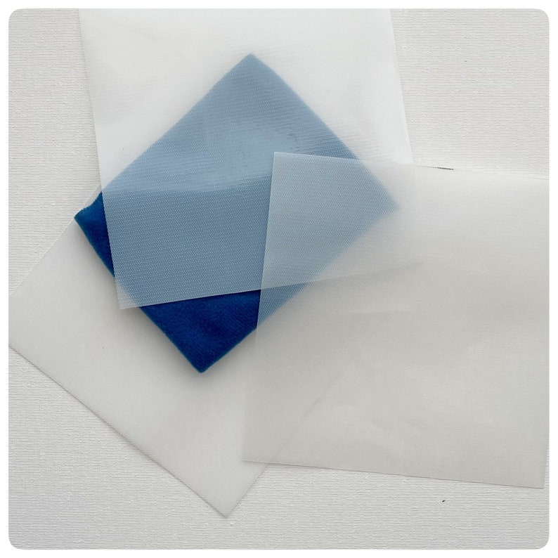 May include: Four sheets of translucent white fabric, one of which is a darker blue color, are stacked on top of each other.