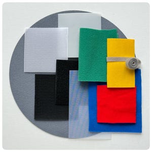 May include: Assortment of fabric swatches in various colors and textures, including black, white, gray, green, yellow, red, and blue. The swatches are arranged in a circle on a gray background.