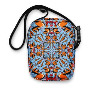 May include: A small blue and orange crossbody bag with a black adjustable strap. The bag features a colorful, intricate pattern of stylized figures and shapes.
