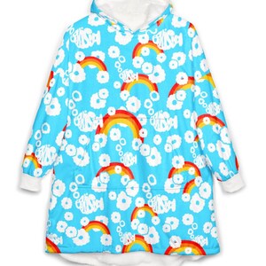 May include: A blue hooded blanket with a repeating pattern of rainbows, white clouds, and text. The blanket has a white fleece lining in the hood and cuffs. The rainbows are red, orange, and yellow.