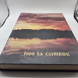 May include: A vintage hardback book with a sunset scene on the cover. The title on the cover reads "1969 la cumbre".