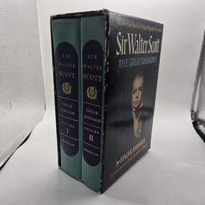 Puede incluir: Un juego de libros en caja titulado "Sir Walter Scott: The Great Unknown" de Edgar Johnson. El juego incluye dos volúmenes con cubiertas verde azulado y letras doradas, y una caja negra con un retrato de un hombre.