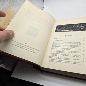 Może przedstawiać: Otwarta książka z kremowymi stronami, czarnym tekstem i czarno-białą ilustracją. Książka wyświetla zawartość i informacje o prawach autorskich. Okładka książki jest brązowa.