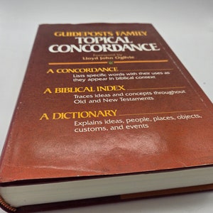 Może przedstawiać: Brązowa książka zatytułowana "Guideposts Family Topical Concordance" autorstwa Lloyda Johna Ogilvie. Książka jest konkordancją, indeksem biblijnym i słownikiem.