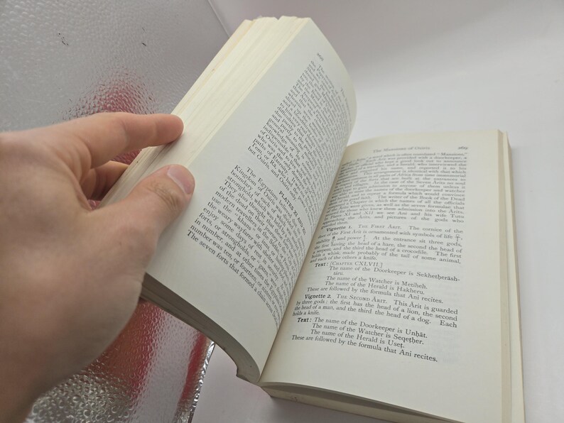 Puede incluir: Un libro abierto con p&aacute;ginas blanquecinas, sostenido por una mano. El texto est&aacute; en ingl&eacute;s, con t&iacute;tulos y p&aacute;rrafos visibles. Las p&aacute;ginas del libro est&aacute;n ligeramente amarillentas. El fondo es una superficie clara y reflectante.