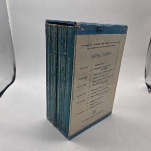 May include: A collection of vintage books from the "Reading for the Junior Great Books Program" Series Three. The books feature teal spines and are housed in a white and blue box. The box displays the volume titles and authors. The books are in good condition.