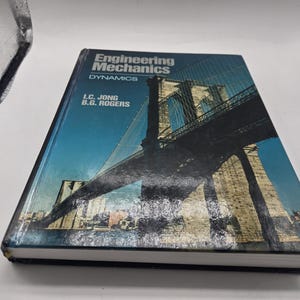 May include: A hardcover book titled "Engineering Mechanics Dynamics" by I.C. Jong and B.G. Rogers. The cover features a bridge illustration with a blue sky background. The book is in good condition.