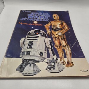 Puede incluir: Un libro de cuentos de Star Wars vintage con fotografías a color. La portada presenta a R2-D2 y C-3PO sobre un fondo estrellado. El título del libro está en texto azul y blanco. El libro está ligeramente desgastado.