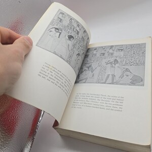 Puede incluir: Un libro abierto con ilustraciones en blanco y negro de arte egipcio antiguo. Las p&aacute;ginas son de color crema y el libro se mantiene abierto. Las ilustraciones representan figuras y jerogl&iacute;ficos.