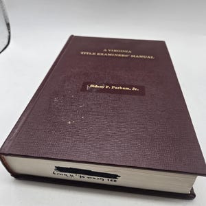 May include: A burgundy hardcover book titled "A Virginia Title Examiner's Manual" by Sidney F. Parham, Jr.