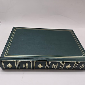 Puede incluir: Un libro de tapa dura verde oscuro titulado "The Odyssey" con detalles dorados. El lomo presenta letras doradas y patrones decorativos. El libro forma parte de la serie "World's Classics".