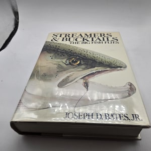 May include: A hardcover book titled "Streamers & Bucktails: The Big Fish Flies" by Joseph D. Bates, Jr. The cover features a watercolor illustration of a fish head with an open mouth and a fishing fly.