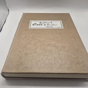 May include: A hardcover book titled "the Story of Colt's Revolver" by Edwards. The book has a light brown cover with a rectangular label in the center. The label features the title and author's name in black text.