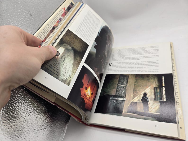 May include: Open book with images and text. The left page shows a series of photographs, including a stone staircase and a fireplace. The right page features a photograph of a person standing near a window. Pages are numbered 216 and 217.