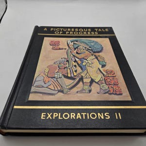 Op de afbeelding: Een hardcover boek getiteld "A Picturesque Tale of Progress" met "Explorations II" in gouden letters. De omslag toont een kleurrijke illustratie van oude figuren. Het boek is zwart met gouden rand.