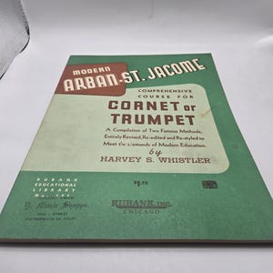 May include: A vintage music book titled "Modern Arban-St. Jacome Comprehensive Course for Cornet or Trumpet." The cover is green and cream with text in brown and white. The book is a compilation of methods by Harvey S. Whistler.