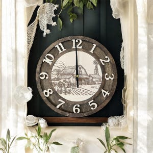 May include: A round wooden wall clock featuring a farmhouse scene. The clock has a dark brown frame with white numerals. The clock hands are black. The background is a dark green colour.