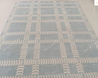 May include: A light blue rug with a white leaf pattern. The rug has a grid pattern with white lines.