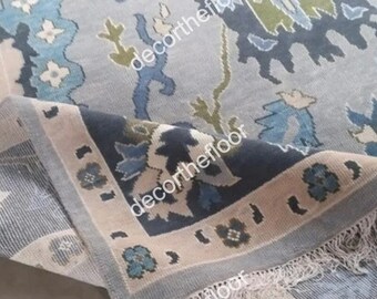 May include: A blue and cream patterned rug with a fringe border. The rug has a floral design with a subtle geometric pattern.
