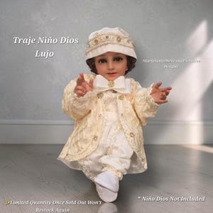 May include: A cream-colored Niño Dios outfit featuring a long-sleeved jacket with intricate lace detailing, a matching cap with beaded trim, a bow tie, and trousers. The text reads Traje Niño Dios Lujo, NlartesaniaMexicanaExclusive Designs, and Niño Dios Not Included.