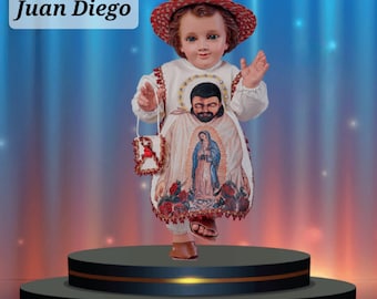 Puede incluir: Una figurita de un niño pequeño vestido con una túnica blanca con un sombrero rojo y blanco. La túnica presenta una imagen de la Virgen María y un hombre con barba. La figurita está de pie sobre una plataforma negra con ribetes dorados. El texto "Juan Diego" es visible en la esquina superior izquierda de la imagen. El texto "TODOS LOS VESTIDOS INCLUYEN ACCESORIOS Y ROPA INTERIOR (PLAYERA Y CALZÓN)" es visible en la parte inferior de la imagen.
