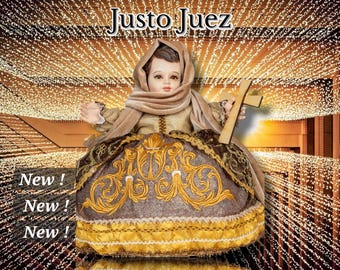 May include: A figurine of a child dressed in a brown and gold gown, holding a wooden cross. The figurine is surrounded by a sparkling background of lights. The text "Justo Juez" is written above the figurine.