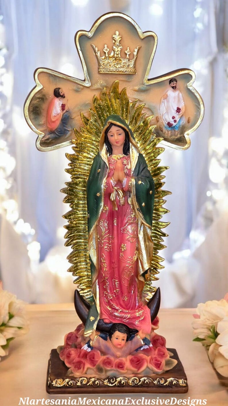 May include: A religious figurine of a woman in a pink and green robe, with a gold halo and cross-shaped backdrop. The figurine is standing on a base with a child and surrounded by roses. The text "NlartesaniaMexicanaExclusiveDesigns" is at the bottom.