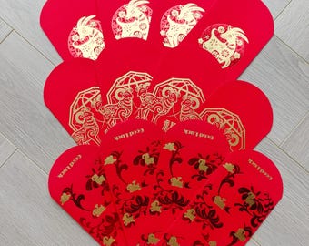 Puede incluir: Una colección de sobres rojos con diseños en lámina de oro. La fila superior muestra ilustraciones de cabras en marcos circulares. La fila central muestra motivos de cabras. La fila inferior presenta patrones florales con el texto Good Luck y 2027.