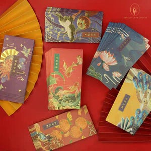 May include: A collection of colorful, decorative red envelopes with various designs, including cranes, koi fish, lotus flowers, and peacock feathers. The envelopes feature gold accents and Chinese characters. The envelopes are arranged on a red surface with a decorative fan.