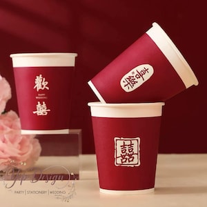 Puede incluir: Tres vasos de papel rojos con bordes blancos están apilados. Cada vaso tiene caracteres chinos blancos impresos. Los vasos son para una boda. El texto en los vasos dice "Happy Wedding".