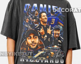 May include: A charcoal gray oversized t-shirt featuring a vintage-style graphic collage of Formula 1 driver Daniel Ricciardo. The design includes multiple images of the driver, a race car, blue lightning accents, and the text DANIEL RICCIARDO.
