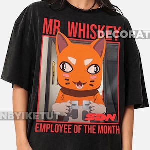 Puede incluir: Camiseta negra con un gato naranja de dibujos animados sosteniendo dos tazas. El texto "MR. WHISKEY" está encima de la imagen, y "EMPLOYEE OF THE MONTH" debajo. Las tazas tienen las letras "SDN".