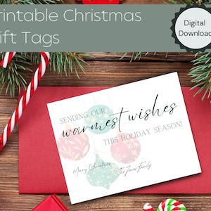 May include: A printable Christmas gift tag with a white background and a design of colorful ornaments. The text on the tag reads "Sending our warmest wishes this holiday season! Merry Christmas The Jones Family".