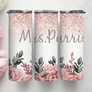 Pu&ograve; includere: Tre bicchieri in acciaio inossidabile con un design glitter oro rosa e un motivo floreale. I bicchieri hanno la scritta "Mrs. Purvis" stampata su di essi.