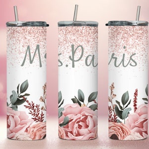 Pu&ograve; includere: Tre bicchieri in acciaio inossidabile con glitter rosa e motivi floreali. I bicchieri hanno coperchi e cannucce. Il bicchiere centrale ha il testo "Mrs. Paris".