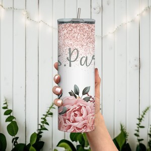 Pu&ograve; includere: Un bicchiere bianco con un design glitter rosa e un motivo floreale. Il bicchiere ha una scritta grigia che dice "S. Parr".