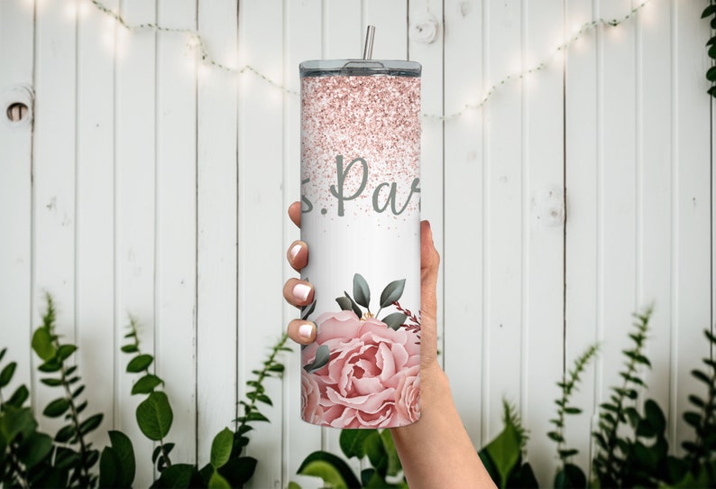 Pu&ograve; includere: Un bicchiere bianco con un design glitter rosa e un motivo floreale. Il bicchiere ha una scritta grigia che dice "S. Parr".