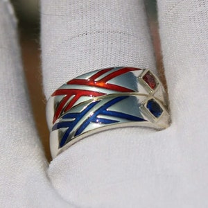 May include: Two silver rings with red and blue enamel designs. The rings are stacked on top of each other and feature small red and blue gemstones.
