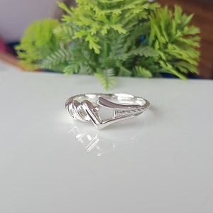 May include: A silver ring with a twisted band and a unique open design. The ring is made of polished silver and has a smooth finish.