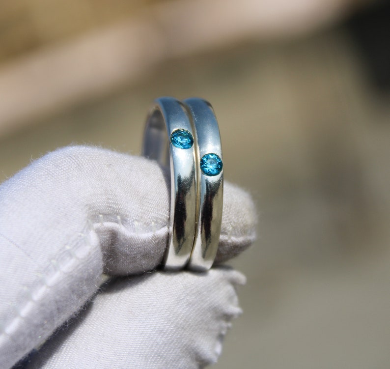 May include: Two silver rings with blue gemstones set into the bands.
