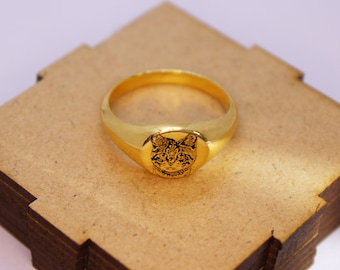 May include: A gold signet ring with a detailed engraving of a cat's face.