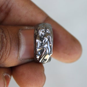 May include: A silver ring with a detailed sculpture of two figures embracing.