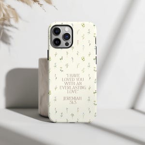 May include: A phone case featuring a floral pattern and the words "I HAVE LOVED YOU WITH AN EVERLASTING LOVE" from Jeremiah 31:3. The case is cream-coloured with tiny green and yellow flowers.