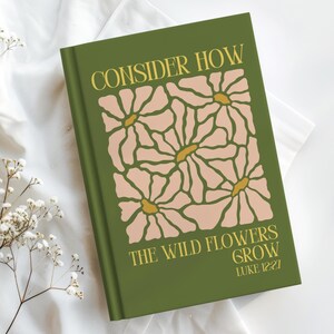 Puede incluir: Un diario verde con el texto "CONSIDER HOW THE WILD FLOWERS GROW" y el versículo bíblico Lucas 12:27. La portada presenta un diseño floral en rosa y amarillo.