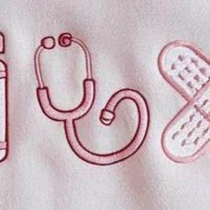 May include: Pink embroidered design featuring a bow, prescription bottle with "Rx" text, stethoscope, crossed bandages, and a drink with a straw. The design is on a white background.