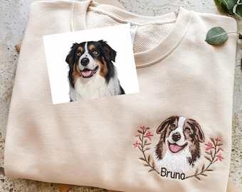 May include: A beige sweatshirt with an embroidered image of a dog with the name "Bruno" underneath. The dog is brown and white with a happy expression. There are pink flowers around the dog.