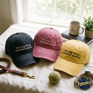 May include: Three baseball caps in black, dusty rose, and mustard yellow, each featuring the embroidered white or black text "this dog thing escalated quickly" on the front panel. The caps have a distressed, washed-out fabric finish.