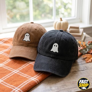 May include: Two baseball caps, one in brown and one in black, each featuring an embroidered white ghost icon on the front panel. The caps have a structured crown, a curved brim, and a washed fabric texture, presented as a pair of headwear items.