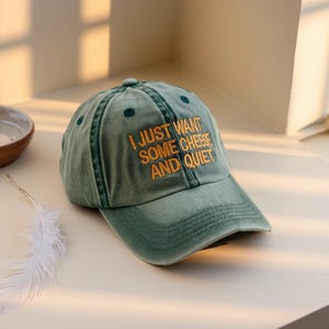 May include: A green baseball cap with the text "I just want some cheese and quiet" embroidered in yellow.