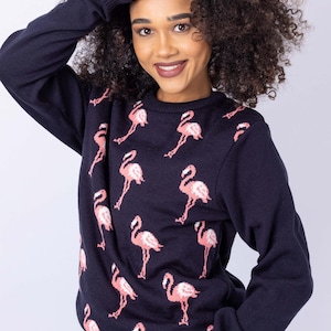 May include: A navy blue sweater with a pink flamingo pattern. The sweater has long sleeves and a crew neck.